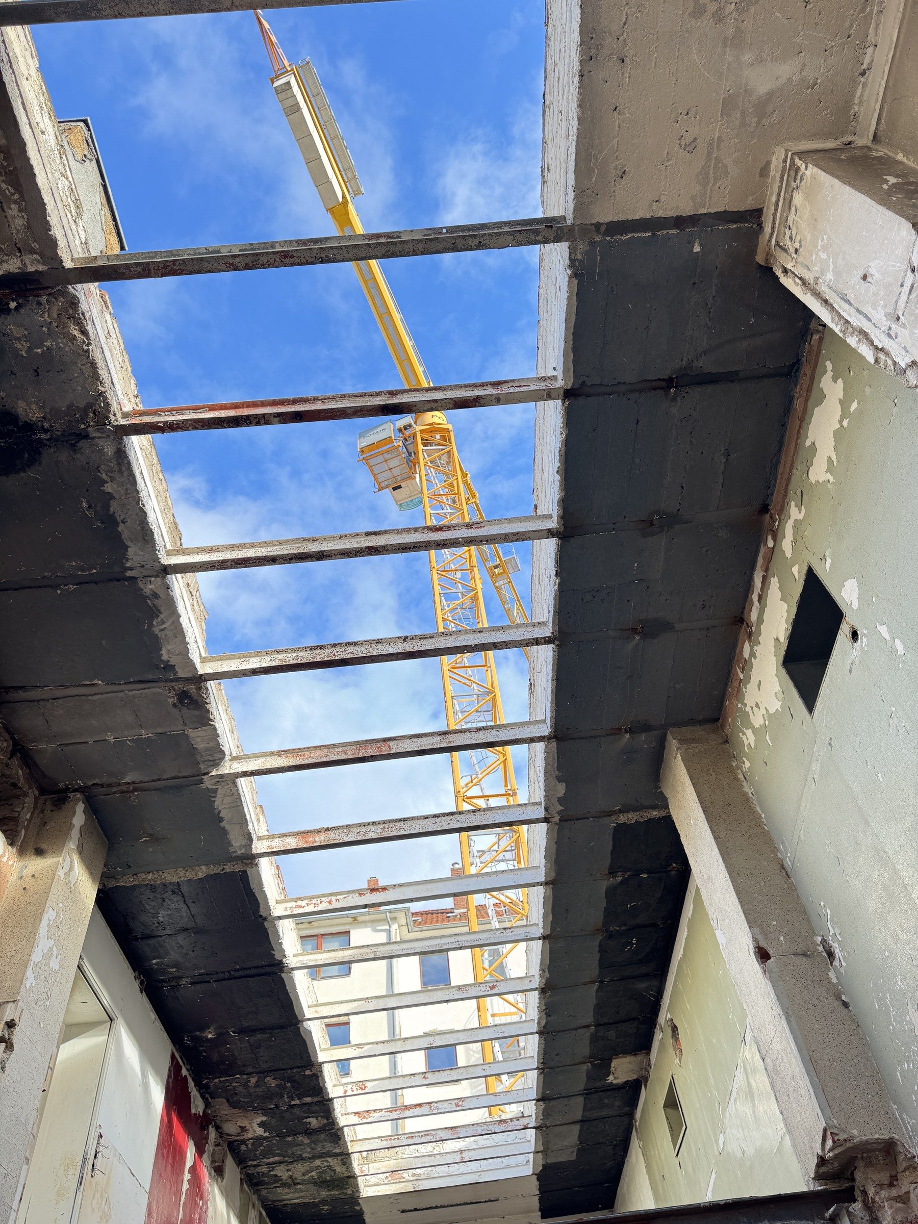 Alte Stahlträger und Oberlichter über der Einfahrt der Halle, dahinter ein Kran